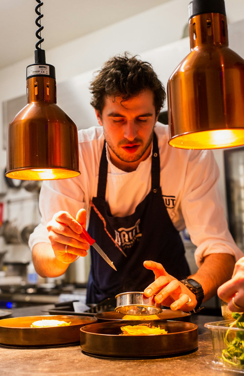 Chef italien plate un dressage sous des lampes en cuivre